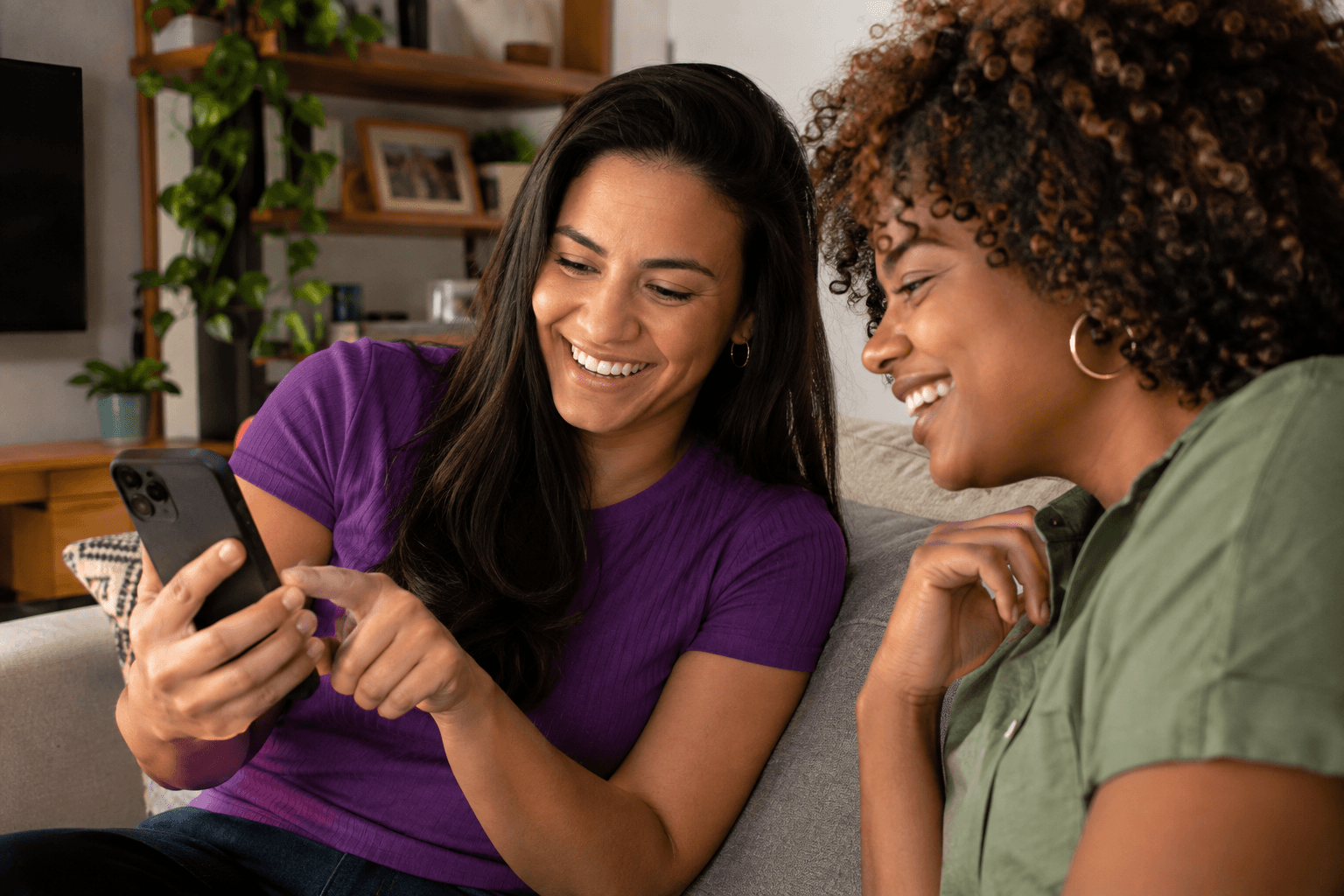 Duas mulheres sorrindo olhando o celular juntas